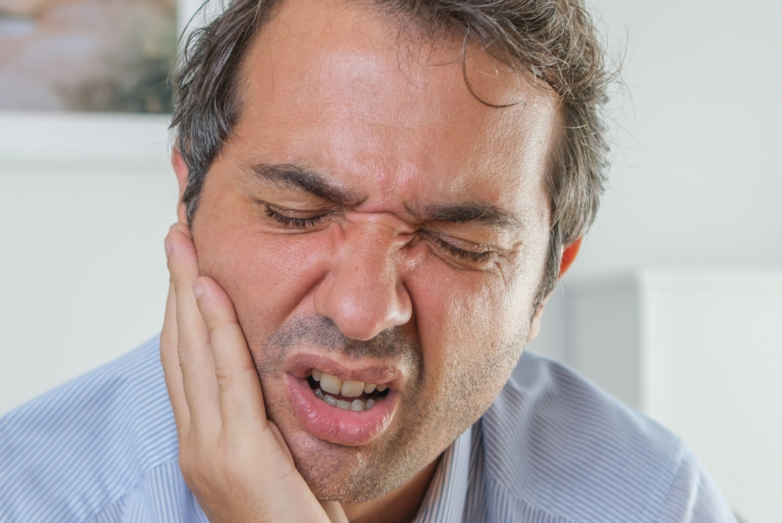 Man suffering toothache sitting at home
